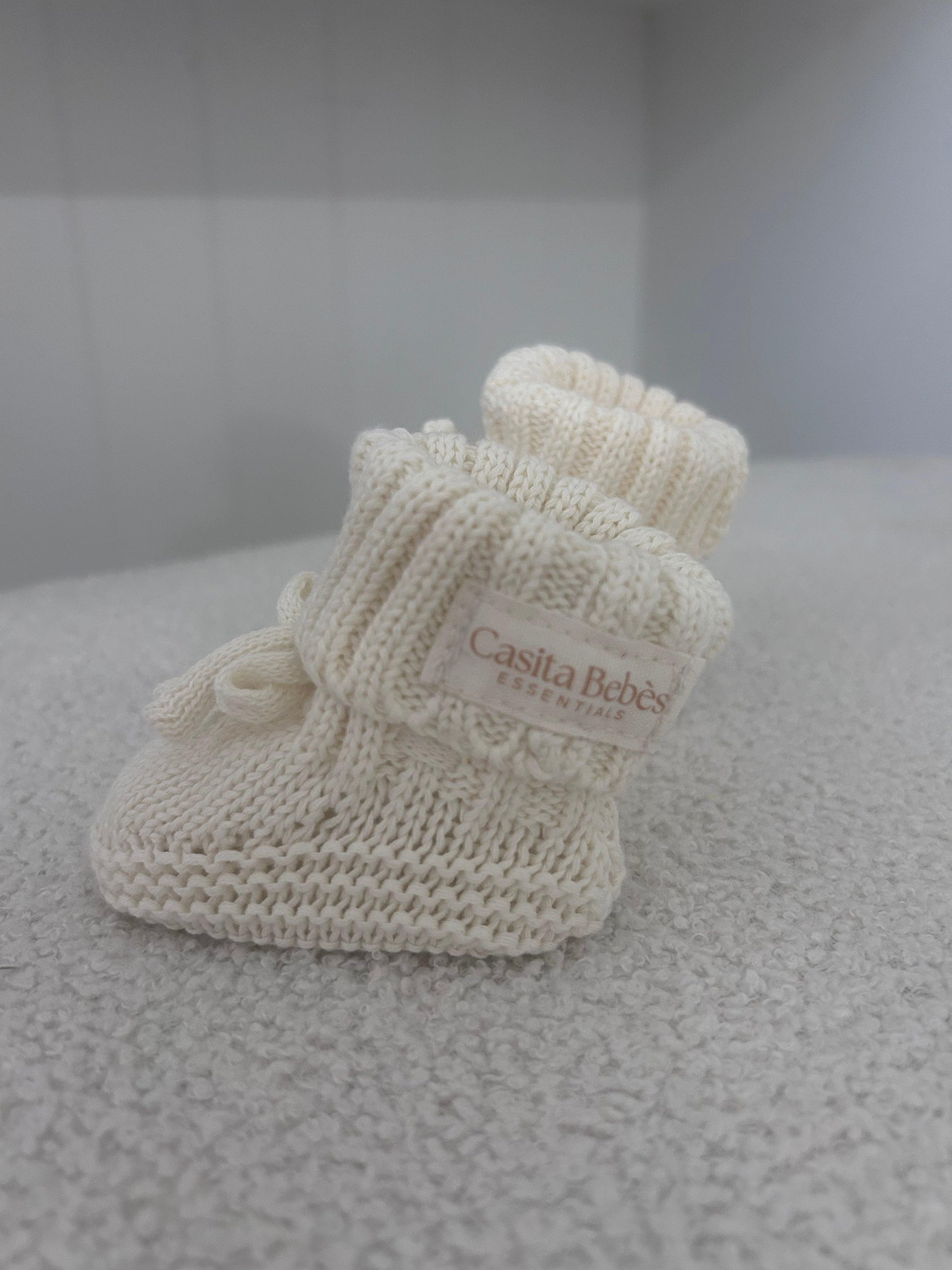 Organic knitted newborn booties with Casita Bebes label, soft certified organic baby clothing.