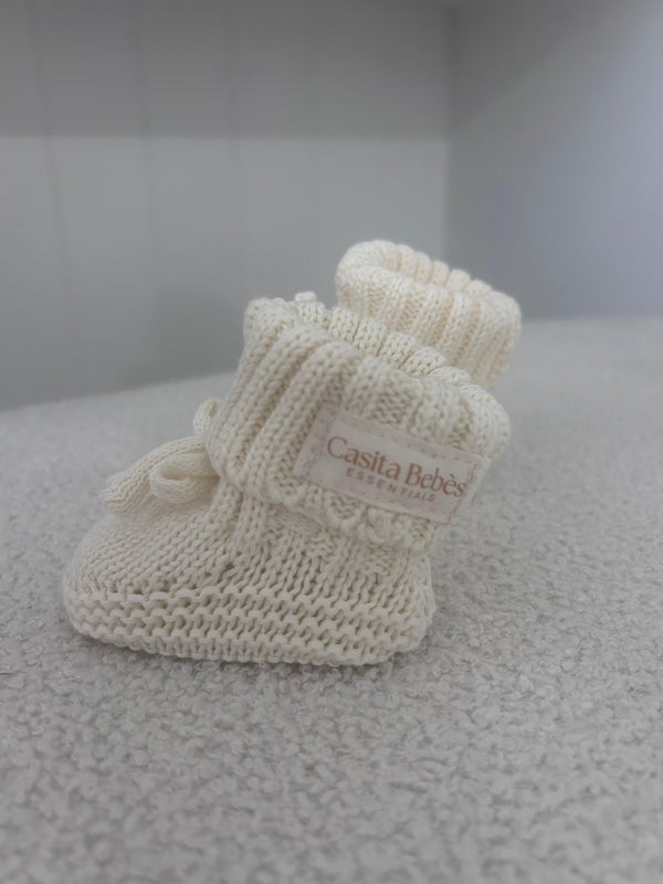 Soft knitted baby booties with Casita Bebès Essentials label, ideal for newborns and infants