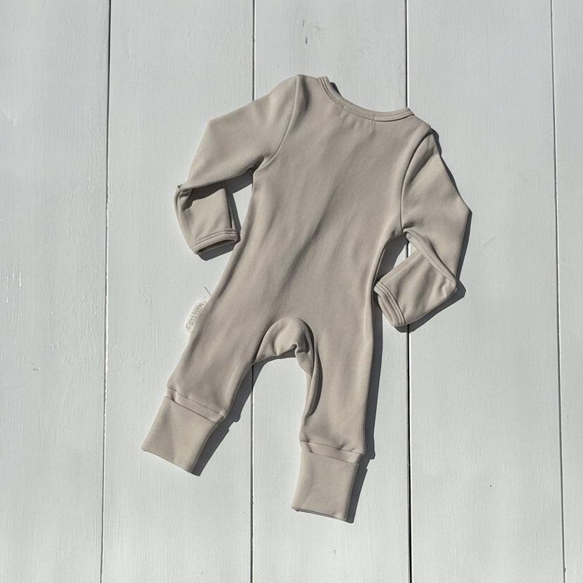 Beige organic baby romper flat lay, long sleeves, ribbed cuffs, certified organic, Casita Bebes baby clothing.