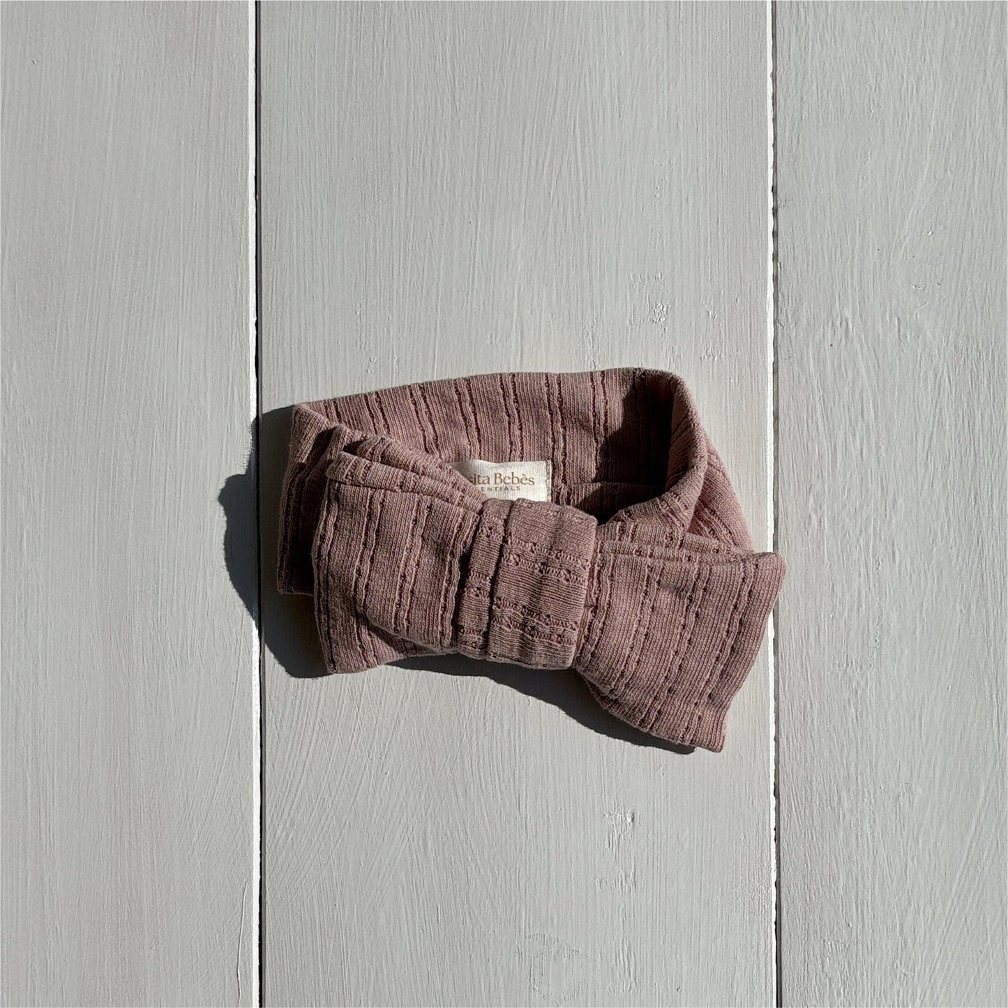 Dusty purple organic cotton baby bow from Casita Bebes Essentials Collection, textured fabric close-up.